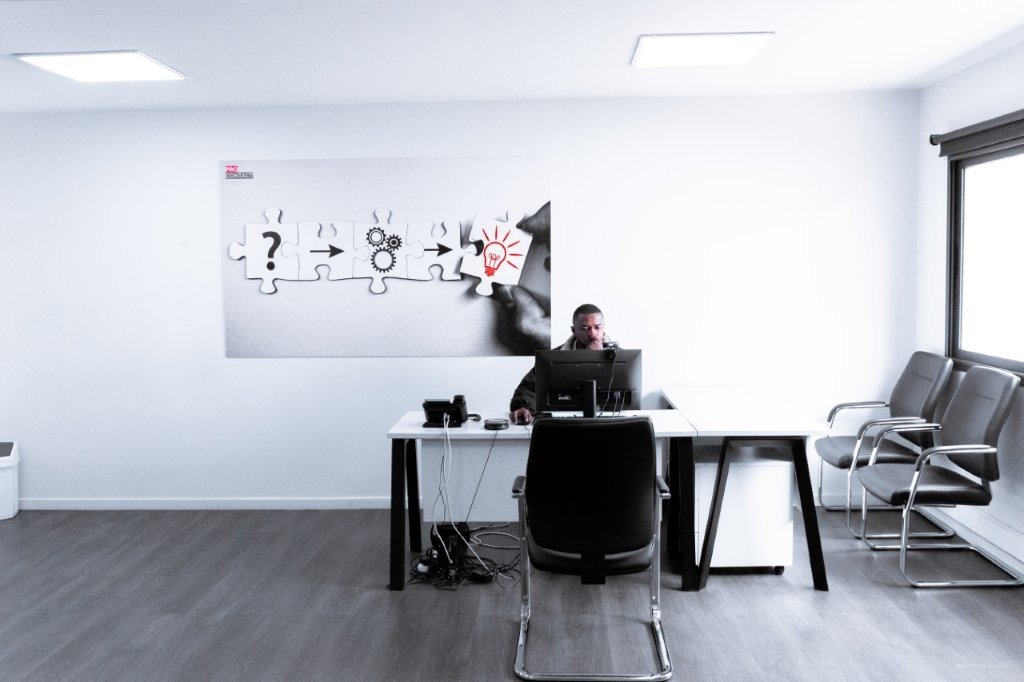 Employé travaillant à un bureau avec tableau puzzle sur le mur.