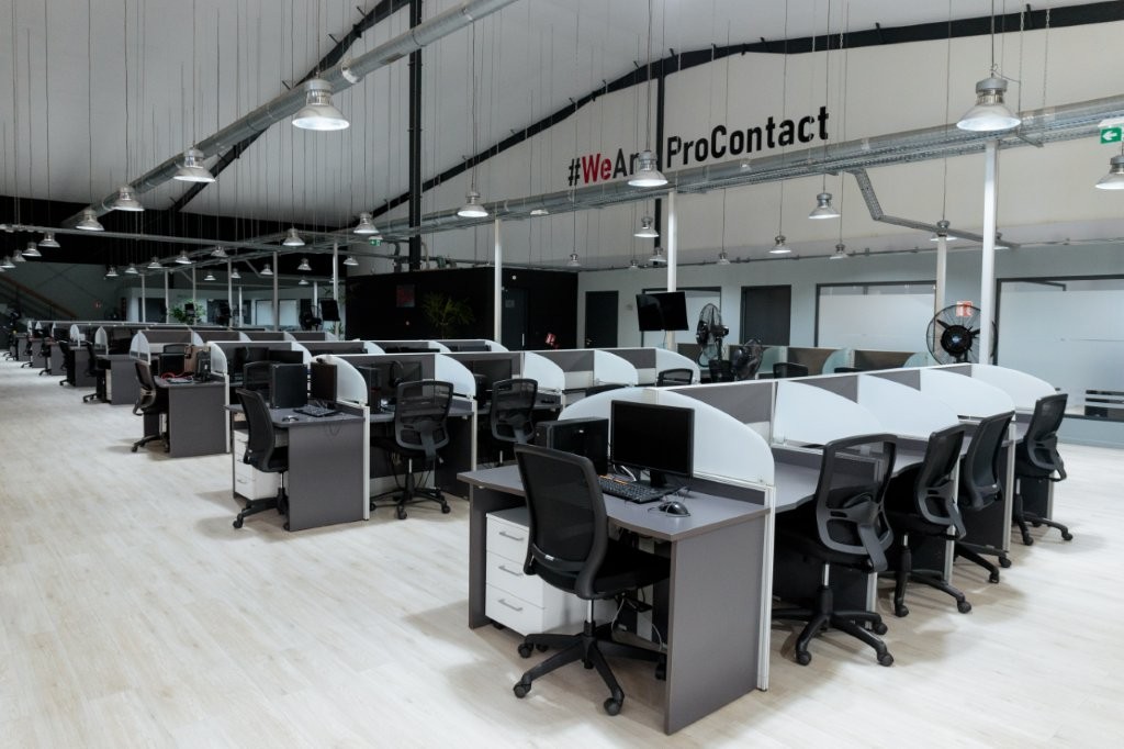 Espace de centre d'appels avec bureaux et chaises ergonomiques.