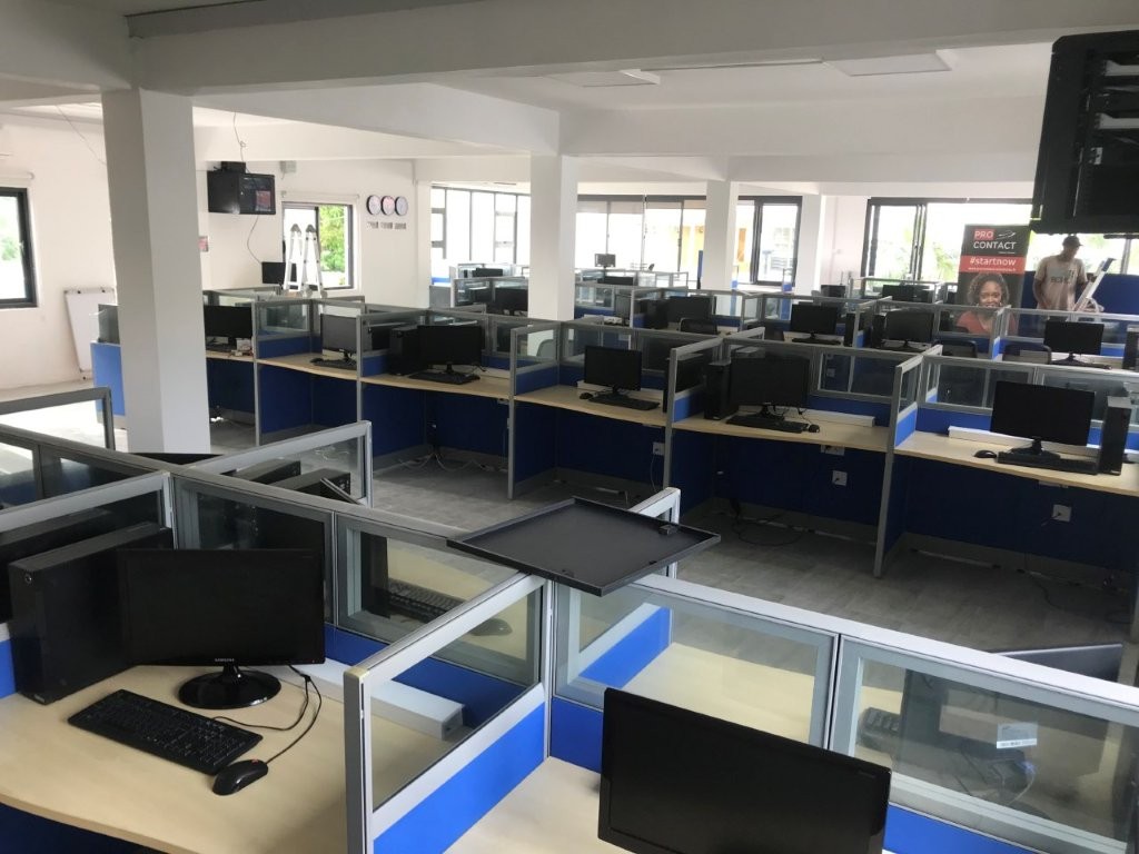 Espace de centre de contact avec ordinateurs et bureaux modernes.