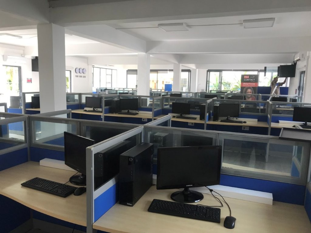 Espace de centre d'appels avec plusieurs postes de travail et écrans.