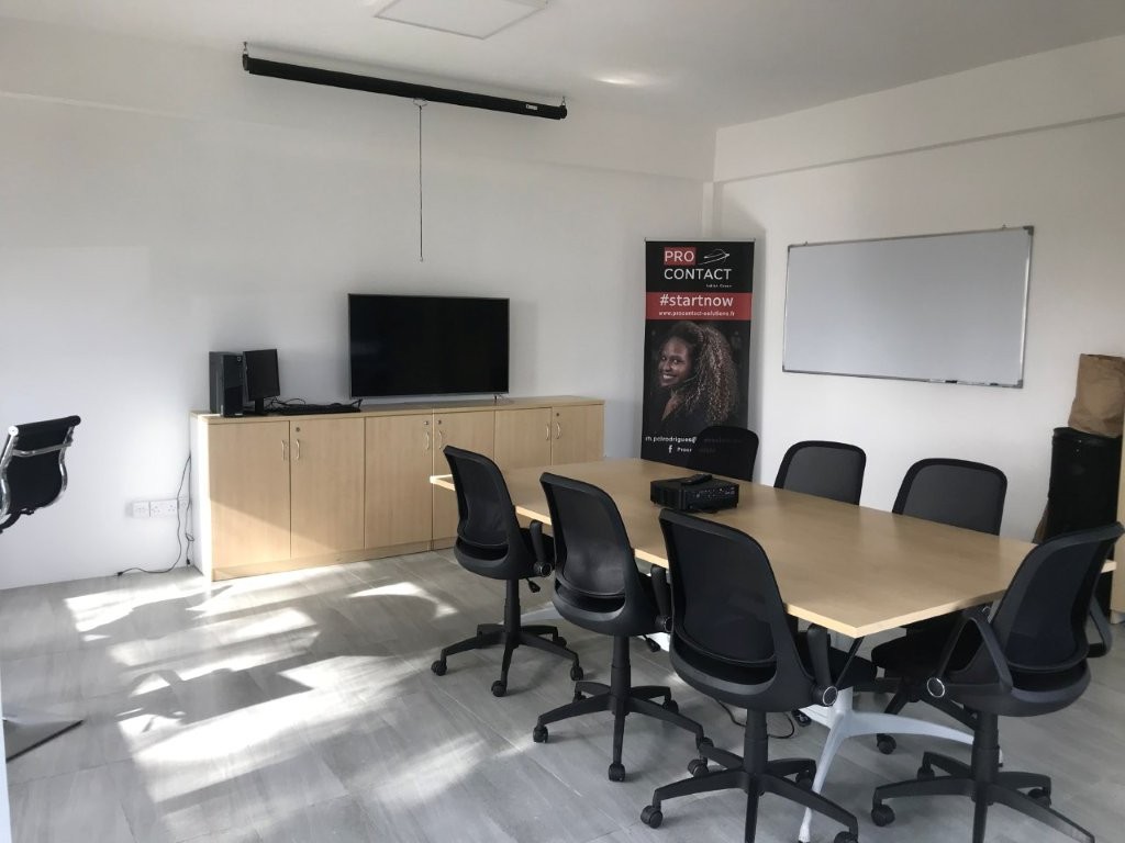 Salle de réunion avec table, chaises et écran TV dans un centre de contact.