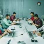 Groupe de collègues en réunion dans une salle de conférence moderne.