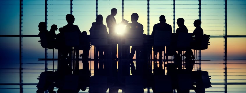 Réunion d'affaires avec silhouettes de personnes dans une salle de conférence.SLA back-office avec suivi des délais et contrôle qualité